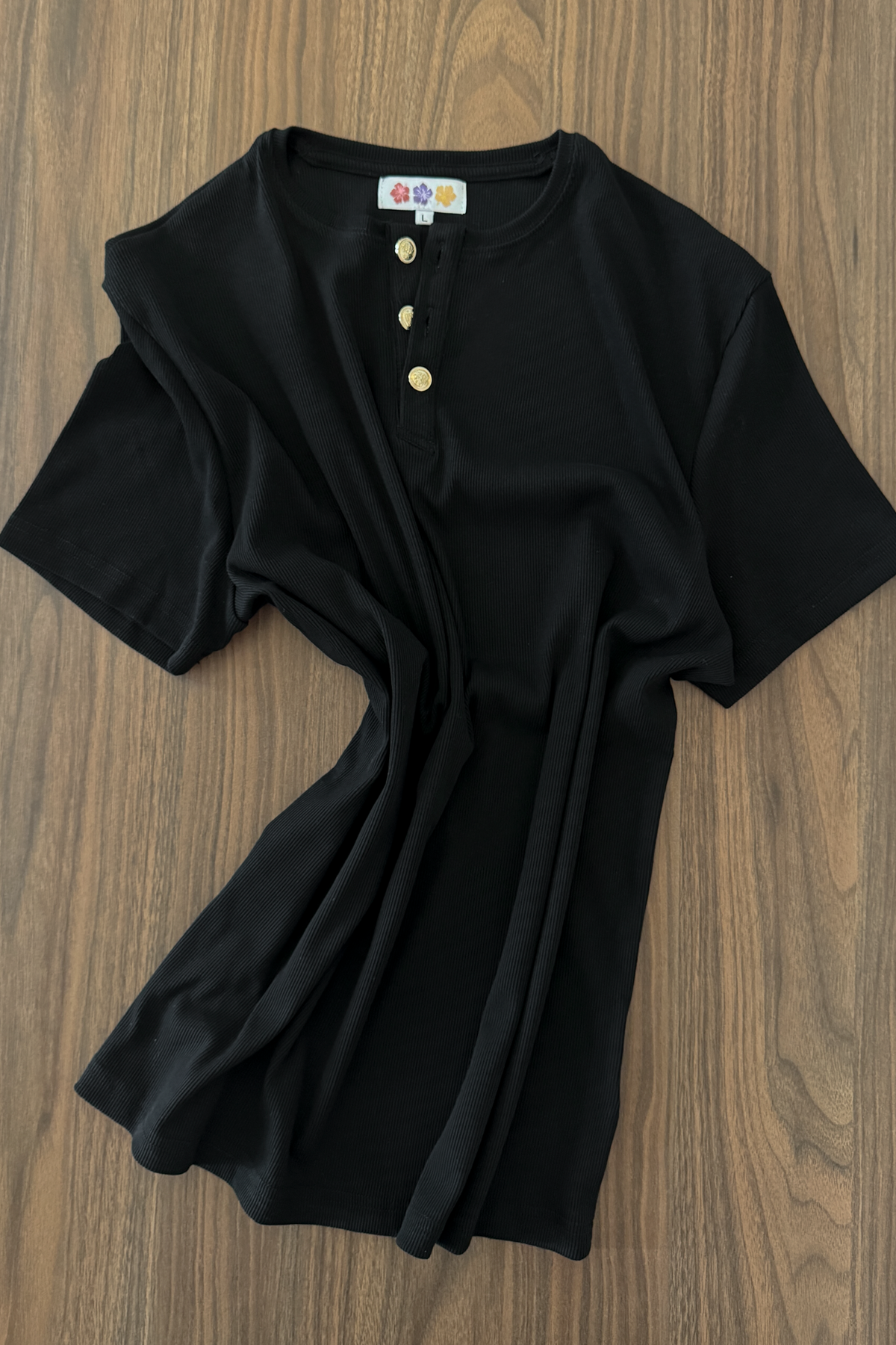 Black Henley Shortsleeve by Rare Humans laid flat on a wooden surface